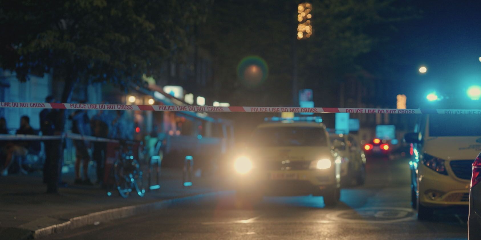 A line of police tape is stretched across a road at night